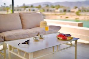 a coffee table with a glass of orange juice and a plate of fruit at Lux Villa Azure 36A in Salalah