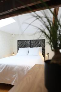 a bedroom with a white bed and a potted plant at Au Lit D'Ô in Bressuire