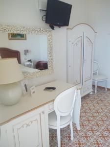 a bedroom with a desk and a bed with a mirror at Hotel La Perla in Praiano +37 photos
