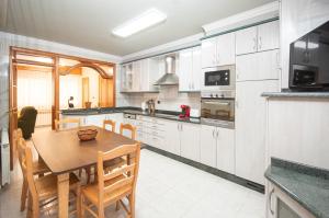 a kitchen with a wooden table and a dining room at AG Piso Río Miño Carballo, a 700m del centro in Carballo
