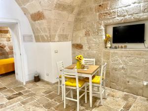 a dining room with a table and chairs and a tv at Antica Pietra in Polignano a Mare