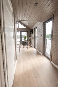 a living room with a table and chairs and windows at Domki na wodzie - Mazury in Ruciane-Nida