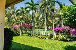 un giardino con palme e fiori rosa di Green Villa Hồ Bơi riêng a Phan Thiet
