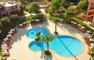 una vista aérea de una piscina con palmeras y sombrillas en Zephyr Targa Marrakech, en Marrakech