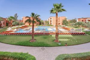 un complejo con piscina, palmeras y sombrillas en Zephyr Targa Marrakech, en Marrakech
