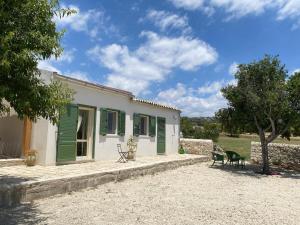 a house with green shutters and a table and chairs at La valle dei carrubi in Scicli