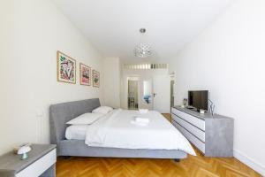 a white bedroom with a bed and a tv at Palais D'orient in Nice