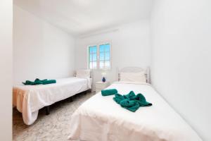 2 Betten in einem weißen Zimmer mit grünen Bögen in der Unterkunft MarySol 2 Apartment with terrace close to the sea in Punta de Mujeres