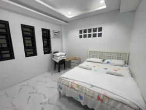 a white bedroom with a bed and a desk at MANEL Guest House - Donsol, Philippines in Donsol