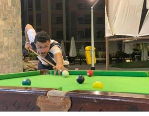 a man is playing pool on a pool table at chalet with garden in grand view I06 in Dawwār ‘Abd Allāh