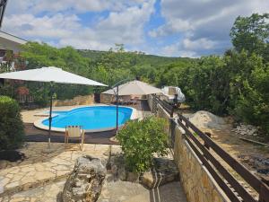 a pool with two umbrellas and a table and chairs at Sunny Pool Apartments in Maslenica