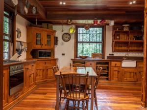 a kitchen with wooden cabinets and a table and chairs at Glentowy Farm Underberg in Underberg