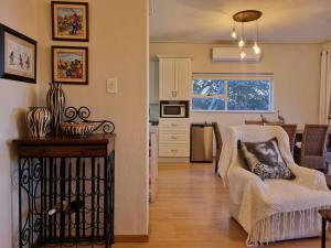 a kitchen and living room with a chair and a table at 'Top Flat' Apartment with Easy Beach Access, Sea front sleeps 5 in Gordonʼs Bay