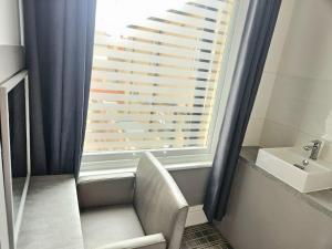 a bathroom with a window with a chair and a sink at Hotel Claytou in Blackpool +54 photos