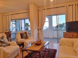 a living room with two chairs and a table at 'Top Flat' Apartment with Easy Beach Access, Sea front sleeps 5 in Gordonʼs Bay