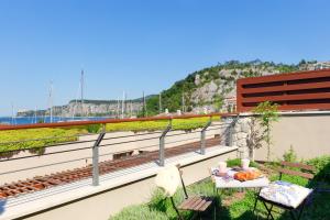 a balcony with a bench and a table with fruit on it at Portopiccolo Apartments - Giardino vista castello in Portopiccolo Sistiana