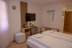 a bedroom with two beds and a desk with a television at Careva Cuprija Apartment&Rooms in Sarajevo