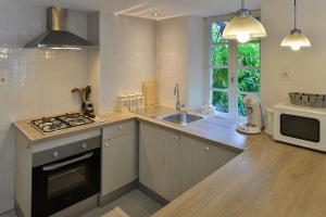 a kitchen with a stove and a sink and a microwave at Le Prieuré Le Pavillon in Souillac