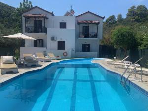 a villa with a swimming pool in front of a house at Skopelos Inn in Stafylos
