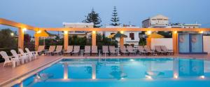 a pool with chairs and a house in the background at Nontas suites in Kato Daratso