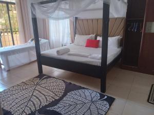 a bedroom with a four poster bed with red pillows at Sunset Sips serviced apt-nyali in Mombasa