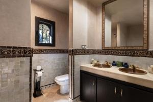 a bathroom with two sinks and a toilet and a mirror at Marrakech Villa with Private Pool & Family-Friendly in Marrakesh