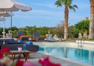a swimming pool with chairs and a table and an umbrella at Fragoulis Village in Parasporos