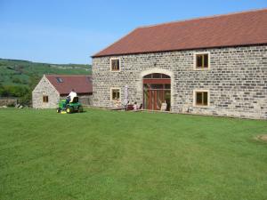 a man on a tractor in front of a brick building at Padley Farm in Bradfield