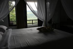 a bedroom with a white bed with a window at Puri Alam Bali in Munduk