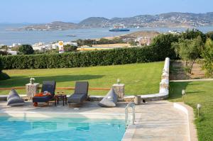 a swimming pool with two chairs and a table next to it at Fragoulis Village in Parasporos