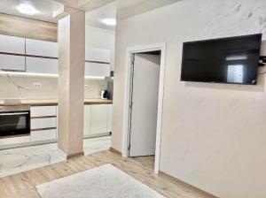 a white kitchen with a flat screen tv on a wall at VN Home 2 in Pomorie