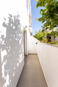 un corridoio di un edificio bianco con un'ombra sul muro di Belka Studios a Vlorë