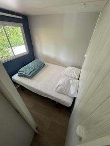 a small bedroom with a bed and a window at europcamping 22 m2 in Fréjus