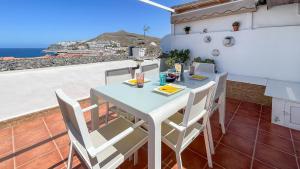 a table and chairs on a balcony with a view of the ocean at Caideros Sunset in Los Caideros