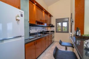 a kitchen with wooden cabinets and a white refrigerator at Salty Pines Villa in Polychrono +17 photos
