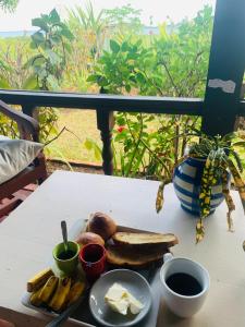 a table with a plate of bread and bananas and butter at La Table d Alexandre Gîte de charme entre mangrove et mer in Hell-Ville