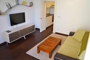 un soggiorno con una TV, un divano e un tavolo di Lumiae Suite a Lecce