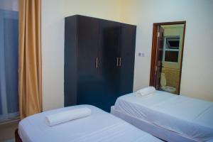 1 Schlafzimmer mit 2 Betten und einem schwarzen Schrank in der Unterkunft Palm Terraces in Mombasa