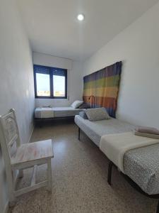 a room with two beds and a chair in it at alquilaencanarias El Medano Spectacular terrace and sea views A in El Médano