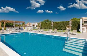 a swimming pool with chairs and umbrellas at White Canvas Boutique Studios in Laganas
