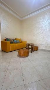 Una sala de estar con un sofá amarillo y una mesa. en Appartement lumineux à Rabat, en Rabat