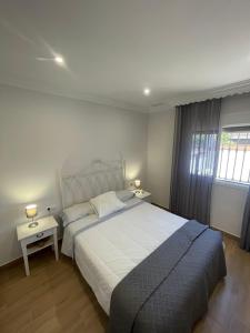 a bedroom with a large white bed and two tables at Sunset Palm in El Puerto de Santa María +13 photos