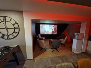 a living room with a large clock and a tv at Un Moment Spa - le Gaïa in Sailly-sur-la-Lys