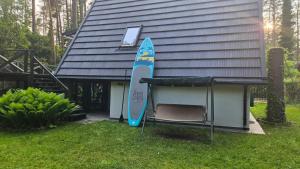 ein Surfbrett und ein Stuhl neben einem Haus in der Unterkunft Domek letniskowy nad jeziorem, Mazury in Teerau