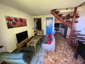 a living room with a couch and a staircase at Les Chardons - Apt duplex vue montagne in Saint-Léger-les-Mélèzes