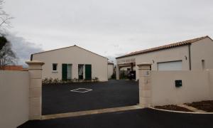 ein weißes Haus mit einem Tor und einem Parkplatz in der Unterkunft La bourbonnaise in Corme-Royal