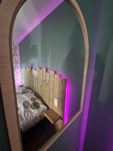 a mirror reflecting a bed in a room with purple lights at Un Moment Spa - le Gaïa in Sailly-sur-la-Lys +32 photos