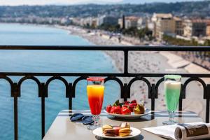 a table with two glasses of juice and a bowl of fruit at Hotel Suisse in Nice