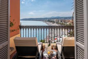 a balcony with chairs and a view of the ocean at Hotel Suisse in Nice