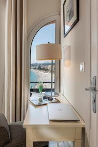 a table with a laptop on it in a room with a window at Hotel Suisse in Nice